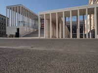 a row of columns is on the street by the building near it on a sunny day