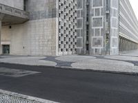 a skateboarder in black jacket riding on concrete street near building with glass windows