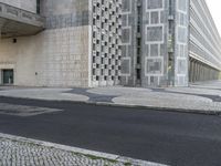 a skateboarder in black jacket riding on concrete street near building with glass windows