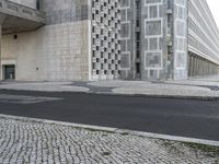 a skateboarder in black jacket riding on concrete street near building with glass windows