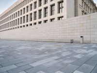 a stone building with many windows in it on a side walk in the city street