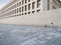 a stone building with many windows in it on a side walk in the city street