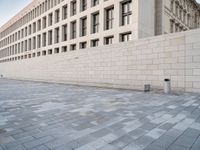 a stone building with many windows in it on a side walk in the city street