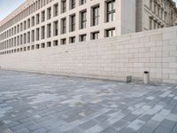 a stone building with many windows in it on a side walk in the city street