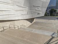 a man that is standing on some stairs in the city with his skateboard and helmet in hand