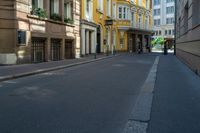 a very narrow alley with some buildings and one man on the sidewalk using a phone