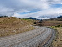 the country road is narrow and empty with rocky corners, and winding road ahead, leading off into mountains