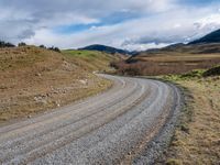 the country road is narrow and empty with rocky corners, and winding road ahead, leading off into mountains