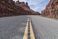 a narrow paved road in the desert in the desert with rocky terrain and a clear blue sky