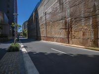 a narrow roadway with a concrete retaining wall along with tall buildings and a street light