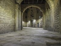 an arched hallway leading to three buildings in a stone area with brick walls and ceilinging