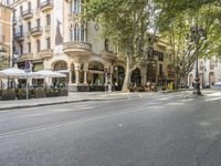 a narrow city street lined with tall trees and restaurants in an upscale area in the background