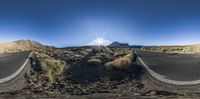 the road from a fisheye lens is narrow and winding through the desert land near the sun