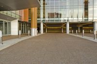 the walkway into the entrance to a building that is open and empty, but with many glass walls