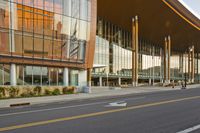 an empty road near a building on a street corner with multiple pillars in front of it