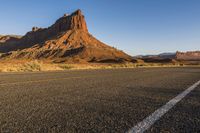 a desert landscape with red rocks and white lines along a long road leading to a mountain