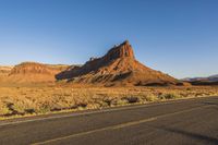 a desert landscape with red rocks and white lines along a long road leading to a mountain