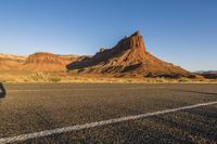 a desert landscape with red rocks and white lines along a long road leading to a mountain