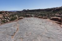 an arid area with some rocks and mountains in the background a bright blue sky is visible