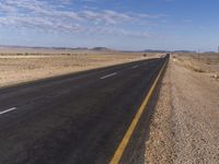 a lone road in the middle of a desert area with no traffic on it on a clear sunny day