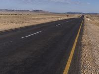 a lone road in the middle of a desert area with no traffic on it on a clear sunny day