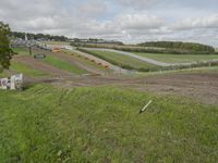 a tractor parked on a hill overlooking a large farm and roadway next to it that is being built