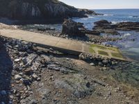 a view of a footpath and bridge near the water in the rocky shoreline of the ocean