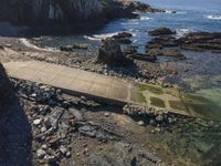 a view of a footpath and bridge near the water in the rocky shoreline of the ocean