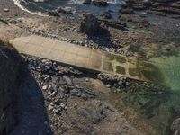 a view of a footpath and bridge near the water in the rocky shoreline of the ocean