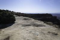 a view from the top of a large rock in a canyon with mountains and hills in the distance