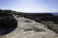 a view from the top of a large rock in a canyon with mountains and hills in the distance