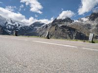 a person on a skate board is sitting on the road with mountains in the background