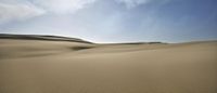 a man is sitting in the desert, looking at the sky and some sand dunes