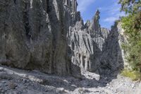 a person with an orange backpack walks across some rocks in a canyon in the mountains