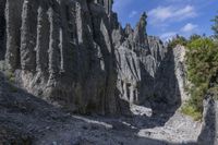 a person with an orange backpack walks across some rocks in a canyon in the mountains