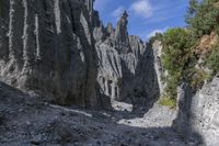 a person with an orange backpack walks across some rocks in a canyon in the mountains