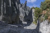 a person with an orange backpack walks across some rocks in a canyon in the mountains