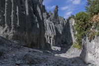 a person with an orange backpack walks across some rocks in a canyon in the mountains