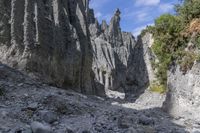 a person with an orange backpack walks across some rocks in a canyon in the mountains