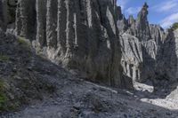 a person with an orange backpack walks across some rocks in a canyon in the mountains