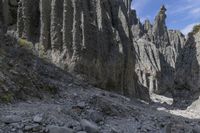 a person with an orange backpack walks across some rocks in a canyon in the mountains