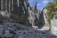 a person with an orange backpack walks across some rocks in a canyon in the mountains