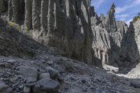 a person with an orange backpack walks across some rocks in a canyon in the mountains