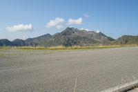 a motorcycle parked on a small mountain side road near mountains with no cars driving on it