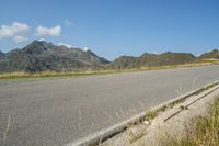 a motorcycle parked on a small mountain side road near mountains with no cars driving on it