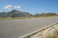 a motorcycle parked on a small mountain side road near mountains with no cars driving on it