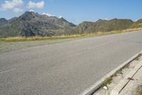 a motorcycle parked on a small mountain side road near mountains with no cars driving on it