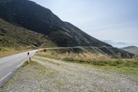 a motorcycle parked on a small mountain side road near mountains with no cars driving on it