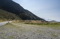 a motorcycle parked on a small mountain side road near mountains with no cars driving on it