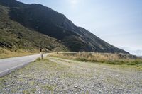 a motorcycle parked on a small mountain side road near mountains with no cars driving on it